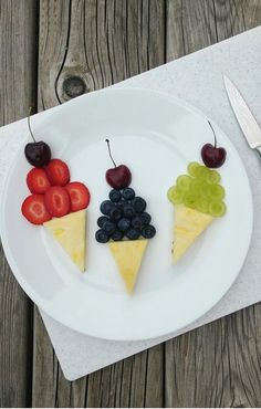 a white plate topped with slices of fruit next to a knife and fork on top of a wooden table