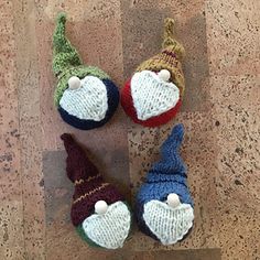 four knitted gnomes sitting on top of a wooden floor