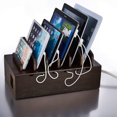 an electronic device charging station with five different devices on it's sides and one plugged into the charger