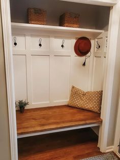 a wooden bench with baskets on top of it in front of a white coat rack