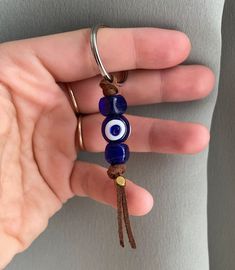 a hand holding a key chain with two evil eyes on it's end and a brown cord