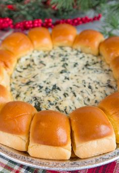 a platter filled with rolls and cheese on top of a table next to christmas decorations