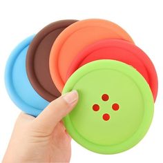 a hand is holding four different colored buttons