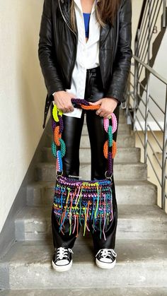 a woman in black leather pants and white shirt standing on stairs with her handbag