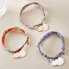 three bracelets with two heart tags on them