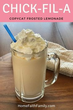 a glass mug filled with whipped cream on top of a wooden table