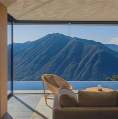 a living room filled with furniture next to a large glass window overlooking the mountain range