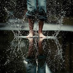 a person standing in the rain with their feet up and water splashing on them