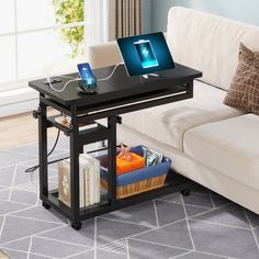 a laptop computer sitting on top of a wooden table next to a white couch in a living room