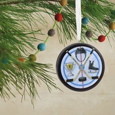 a christmas ornament hanging from a pine tree with hockey gear and pucks on it