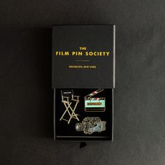 the film pin society's brochure is displayed in its box on a black surface