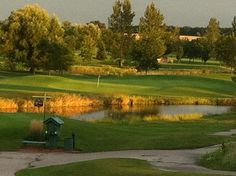 a golf course with water and trees in the background