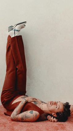 a woman laying on the ground with her legs crossed and shoes hanging off top of her head