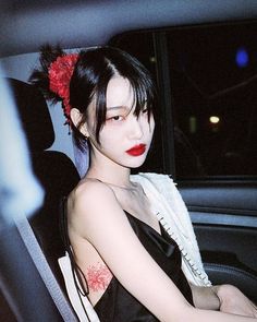 a woman sitting in the back seat of a car with red lipstick on her face