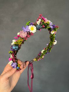 a hand holding a flower crown made out of flowers