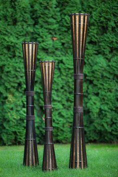 three tall metal vases sitting in the grass