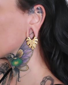 a close up of a person with tattoos on their neck and behind them is a butterfly earring