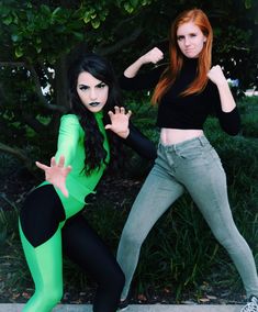 two women in green and black outfits posing for the camera with their arms stretched out