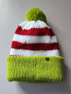 a green and red knitted hat with a pom - pom