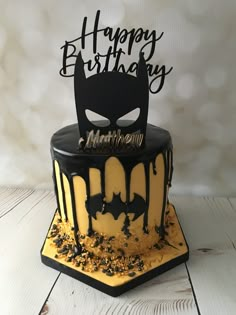 a birthday cake decorated with black and yellow icing on a white wooden table top