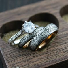 two wedding rings sitting on top of each other in a wooden ring box with wood and diamond accents