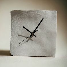 a clock made out of white paper with black hands