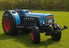 a blue tractor parked on top of a lush green field