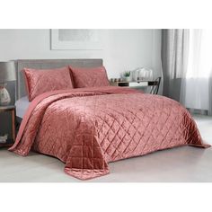 a bed with a pink comforter and pillows