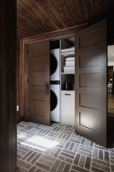 an open door to a washer and dryer in a room with wood paneling