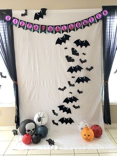 halloween decorations on display in front of a white backdrop with black bats and pumpkins