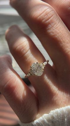 a person's hand with a diamond ring on top of their thumb and fingers