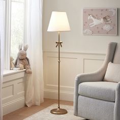 a room with a chair, lamp and stuffed animal on the window sill in it