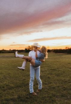 a man carrying a woman on his back in the middle of a field at sunset