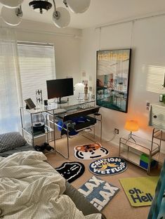 a bedroom with a bed, desk and computer monitor on top of the desk in front of a window