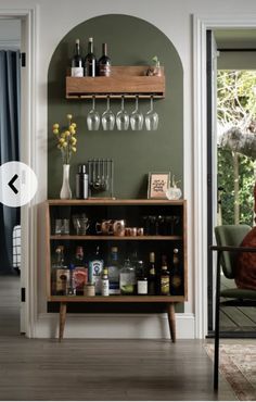 a bar with wine glasses and liquor bottles on the top shelf next to a chair