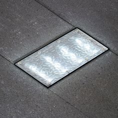 a metal grate sitting on the side of a sidewalk