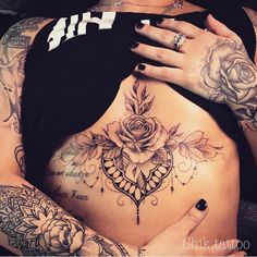 a woman has tattoos on her stomach and is holding the other side of her belly