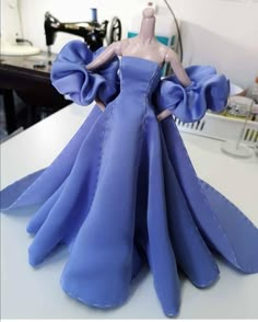 a blue dress is sitting on top of a sewing machine and it's made out of paper