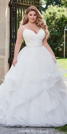 a woman in a white wedding dress posing for the camera with her hands on her hips