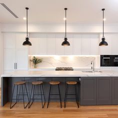 an image of a kitchen setting with bar stools and island in the middle that has marble countertops