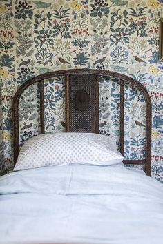 an old iron headboard in front of a floral wallpapered wall with birds on it