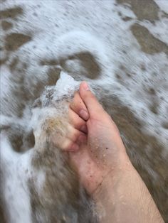 a person's foot in the water with their hand on top of it,