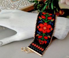 a close up of a bracelet on a white glove with flowers in the back ground