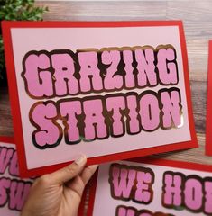 someone is holding up some greeting cards with the words grating station on them in pink and red