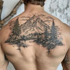 a man with a tattoo on his back is looking at the mountains and trees in the water