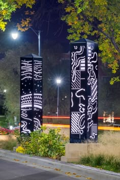 two black and white sculptures sitting on the side of a road next to a park