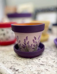 three cups sitting on top of a counter with purple flowers painted on the cup and saucer