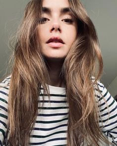 a woman with long brown hair is posing for the camera while wearing a striped shirt