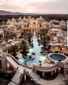 an aerial view of a large building with a pool in the middle and palm trees around it