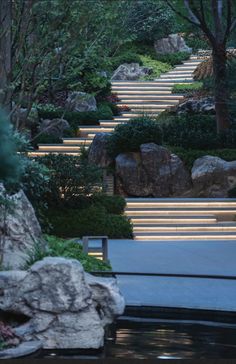 the steps are lit up by lights in the garden at night, along with rocks and trees